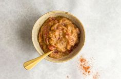 a bowl filled with food sitting on top of a white counter next to a wooden spoon