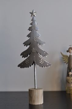 a small metal christmas tree sitting on top of a wooden table next to an angel figurine