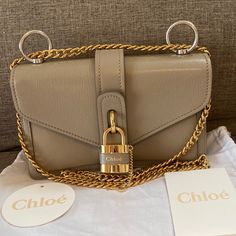 This Stylish Handbag Is Crafted Of Grained Goatskin And Calfskin Leather In Grey. The Bag Features A Gold Chain Shoulder Strap And A Crossover Flap Accented With A Gold Lock And Key. The Flap Opens To A Partitioned Beige Leather Interior With Zipper And Patch Pockets. Base Length: 9.25 In Height: 6 In Width: 3.25 In Drop: 12 In Drop: 20.5 In Luxury Gray Shoulder Bag, Luxury Gray Shoulder Bag With Palladium Hardware, Designer Gray Shoulder Bag With Gold-tone Hardware, Luxury Beige Bags With Lock, Luxury Beige Bag With Lock, Luxury Crossbody Shoulder Bag With Lock, Luxury Lock Crossbody Shoulder Bag, Luxury Gray Shoulder Bag With Silver-tone Hardware, Designer Crossbody Shoulder Bag With Lock