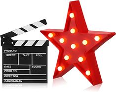 a red star shaped light up sign next to a movie clapper with lights on it