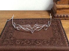 Beautiful Elven circlet made from metal wire with wire wrapping accents. Perfect addition to any outfit or costume.   Item can be secured using hair clips or a ribbon.  A chain can be added to the back for free if requested upon checkout. These pieces are hand made to order and will have some very slight difference.  Made with Aluminum wiring. Aluminum wire is a softer wire and can be bent out of shape if care isn't taken. LOOK IN MY SHOP FOR POSSIBLE DISCOUNT COUPON CODES Fae Crown, Twig Crown, Elf Tiara, Elven Circlet, Elf Crown, Wire Crown, Fairy Crown, Elven Jewelry, Princess Fairy