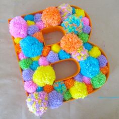 the letter b is made up of pom - poms and plastic letters that are multicolored