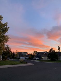 the sky is pink and blue as the sun goes down in this residential area with houses