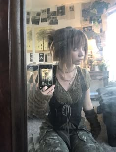 a woman sitting on the floor taking a selfie in front of a mirror with her cell phone