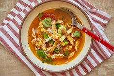 a bowl of chicken tortilla soup on a red and white striped napkin with a spoon