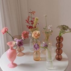 there are many vases on the table with flowers in them and one is pink