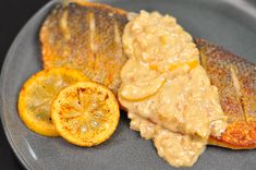 fish fillets with sauce and lemon slices on a gray plate, ready to be eaten