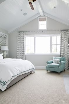 a bedroom with a bed, chair and ceiling fan in the middle of the room