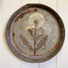 a metal plate with a dandelion painted on it