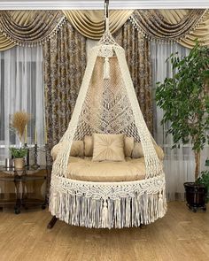 a hammock hanging from the ceiling in a living room with wood flooring