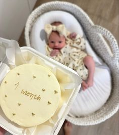 a baby is in a white box with a name on it and the cake has been made to look like an infant