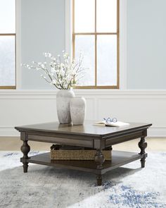 a coffee table with flowers in a vase on top