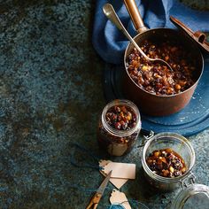 three jars filled with food sitting on top of a blue tablecloth next to utensils