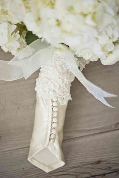 a bridal bouquet with white flowers and pearls on the bottom is sitting on a wooden surface