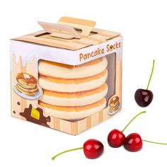 a box of pancakes and two cherries on a white background