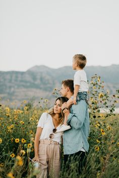 a woman and two children are standing in the middle of a field with wildflowers