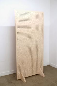 a white pegboard with holes on it in a corner next to a wall and floor