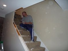 a man sitting on top of a set of stairs next to a stair case in a house