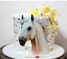 there is a cake decorated with a horse and flowers on the top, as well as an image of a white horse's head