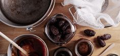 an assortment of food items on a wooden table including dates, jams and spoons