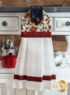 a kitchen with white cabinets and an apron hanging on the wall