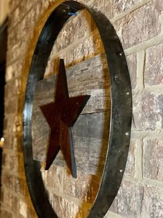 a wooden star hanging from the side of a brick wall next to a metal circle