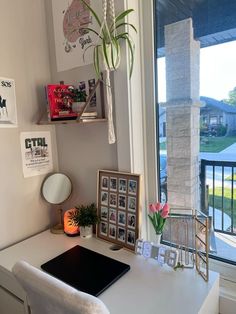 a white desk with a laptop computer on top of it next to a large window