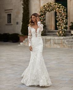 a woman in a white wedding dress standing on a stone walkway with her back to the camera