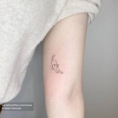 a small cat tattoo on the left inner arm and shoulder, it looks like an outline