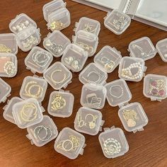 there are many different types of jewelry in the plastic containers on the table next to a mirror