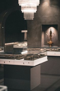 a chandelier hanging from the ceiling in a room filled with glass and metal items