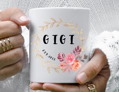 a woman holding a coffee mug with the word gig on it and flowers in front of her