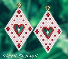 two red and white diamond shaped earrings with green heart in the center on a leafy background