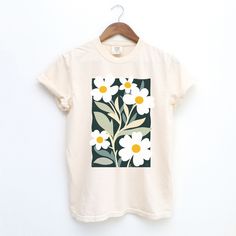 Add a touch of artistic charm to your wardrobe with this 100% cotton Comfort Colors T-shirt, featuring a vibrant graphic of daisy flowers inspired by Henri Matisse's iconic cutout style. A light washed/worn effect has been added to the design. Soft, durable and with an unique design, this tee combines comfort with bold, expressive art for a one-of-a-kind look. Perfect for everyday wear or as a unique gift. The soft-washed, garment-dyed fabric brings extra coziness to your wardrobe while the relaxed fit makes it an excellent daily choice. The double-needle stitching throughout the tee makes it highly durable while the lack of side-seams helps the shirt retain its tubular shape. ✔️ 100% Cotton Comfort Colors T-shirt ✔️ Soft, durable fabric with a relaxed fit ✔️ Ideal for casual wear or gifti White Watercolor Print T-shirt For Spring, Artistic Floral Print Tops For Spring, Artistic Cotton Floral Print Tops, Artistic Cotton Tops With Floral Print, Artistic Cotton Top With Floral Print, Artistic Cotton Tops For Spring, Botanical Graphic Print Cotton Shirt, White Botanical Screen Print Tops, White Botanical T-shirt With Floral Print