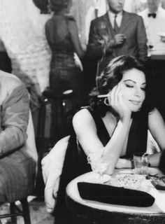 black and white photograph of two people sitting at a table with drinks in front of them