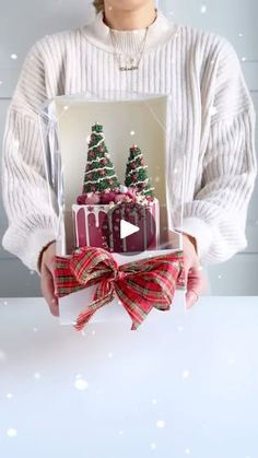 a woman holding a card with christmas trees on it and presents in front of her