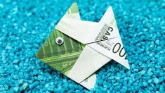 an origami bird made out of money sitting on blue colored carpeted area