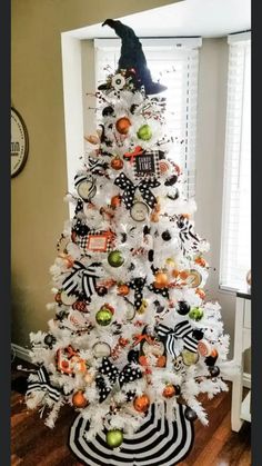 a white christmas tree decorated with black and orange ornaments