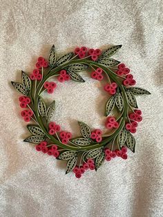 a wreath made out of red flowers and green leaves on a white background with the letter c in the center