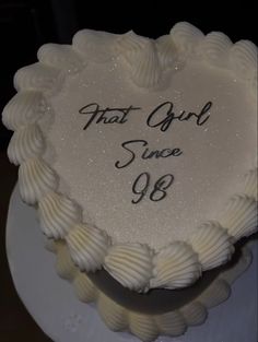 a white heart shaped cake with the words that girl since 90 on it's side