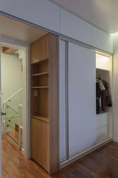 an open closet in the middle of a room with wooden flooring and white walls