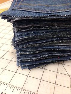 a pile of blue jeans sitting on top of a white tiled floor next to a ruler