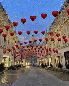 red hearts hanging from the ceiling in an indoor shopping mall with lights strung over it