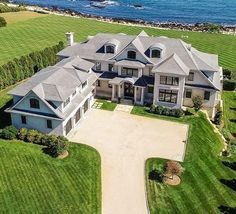 an aerial view of a large house with lots of grass and water in the background