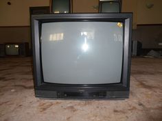 an old television sitting on top of a table in front of two other tvs