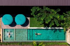 an aerial view of a swimming pool with two people in it and trees surrounding the pool