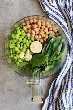 a food processor filled with green vegetables and chickpeas