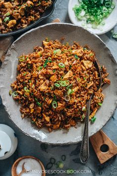 a bowl filled with rice and meat on top of a table next to other dishes