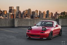 a red sports car parked in front of a city skyline