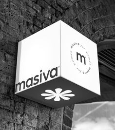 black and white photo of the logo for masiva on a brick wall under a bridge